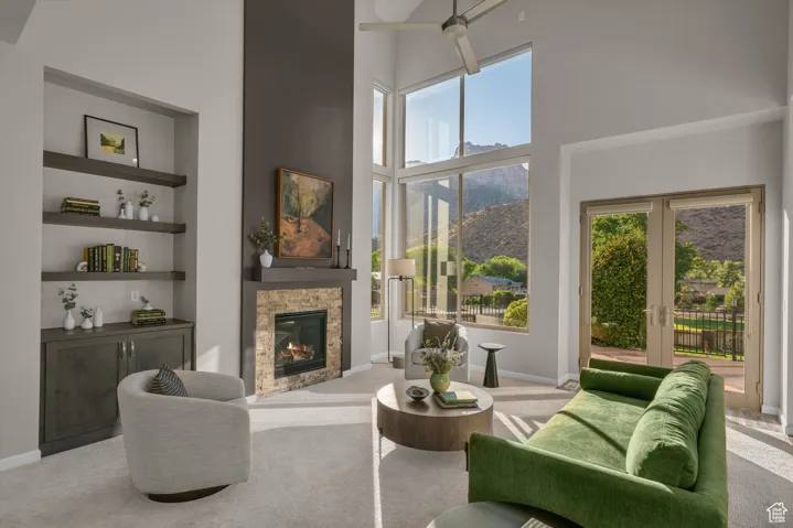 Living room with a high ceiling, carpet floors, built in features, a stone fireplace, and a mountain view