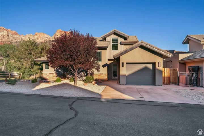 View of front of property featuring a garage, concrete driveway, stone siding, stucco siding, and a tiled roof