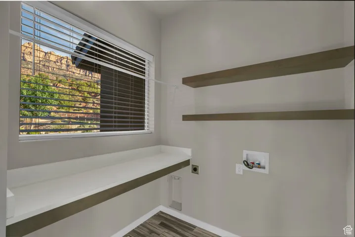 Laundry area with hookup for an electric dryer, hookup for a washing machine, and dark wood-style floors