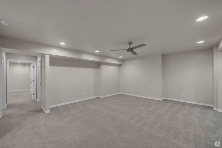 Basement featuring light carpet, ceiling fan, and recessed lighting