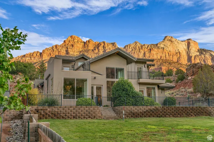Back of house featuring stucco siding, a balcony, and a mountain view