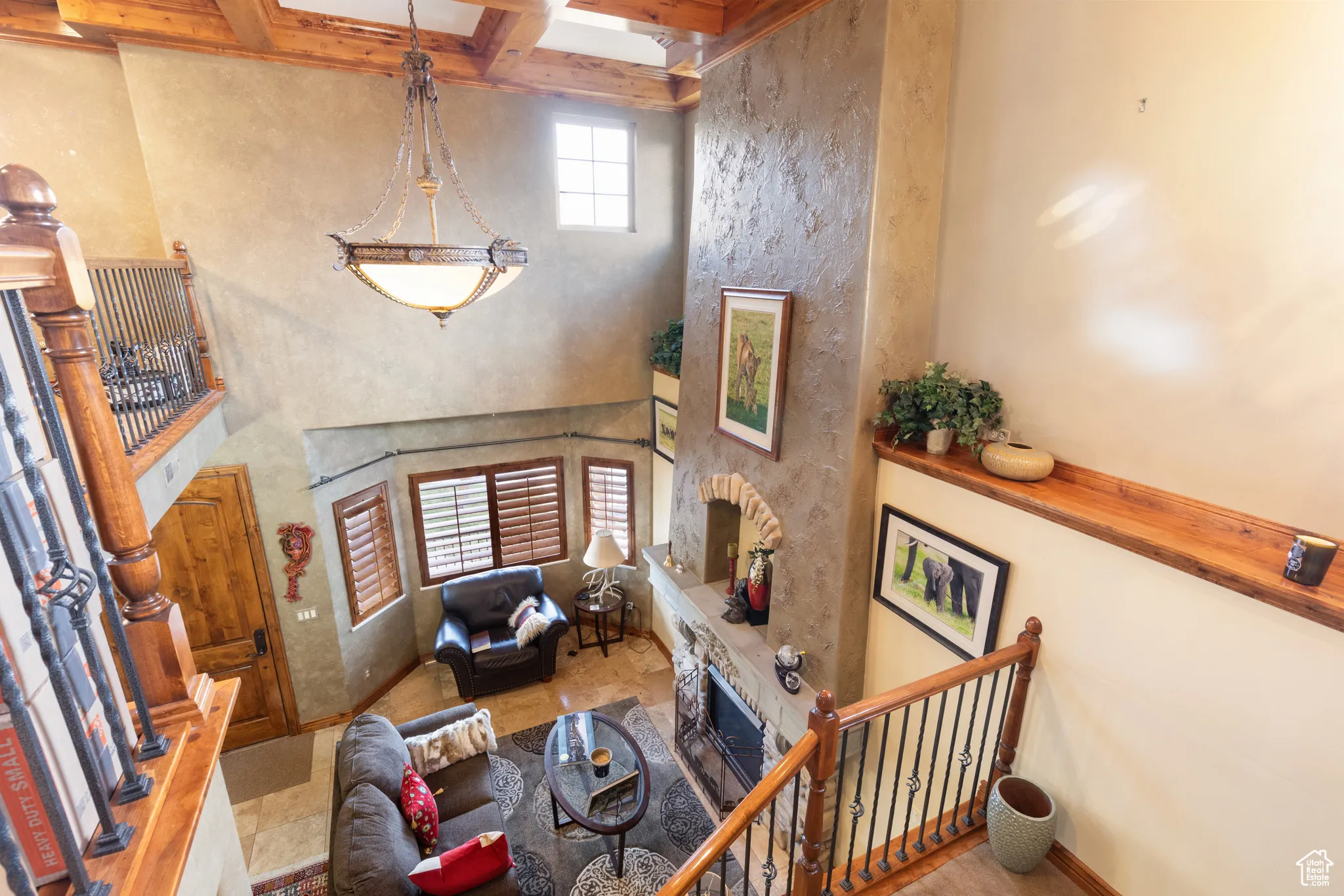 Living area featuring a stone fireplace, a high ceiling, beam ceiling, and tile patterned flooring