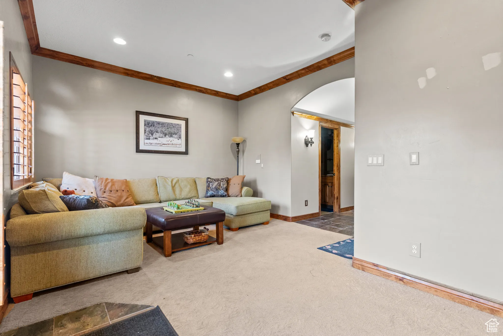 Carpeted living area with arched walkways, ornamental molding, and recessed lighting