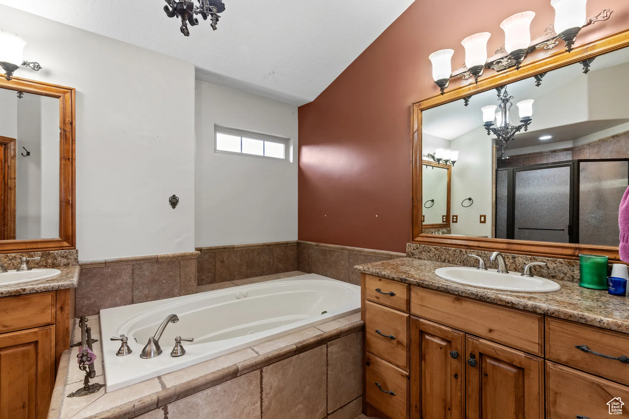 Full bathroom with two vanities, a garden tub, vaulted ceiling, a chandelier, and a shower stall