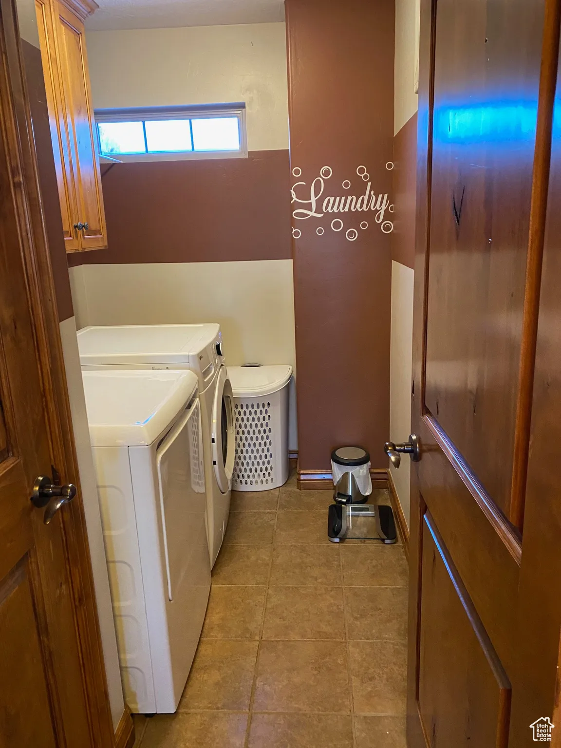Laundry room with cabinet space, light tile patterned flooring, and washer and dryer