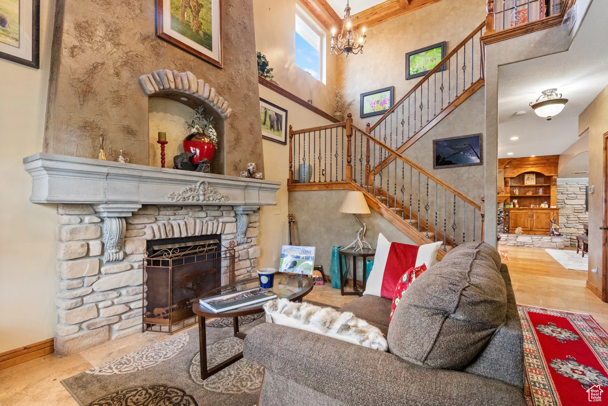 Living room featuring a fireplace, a towering ceiling, a chandelier, and stairs