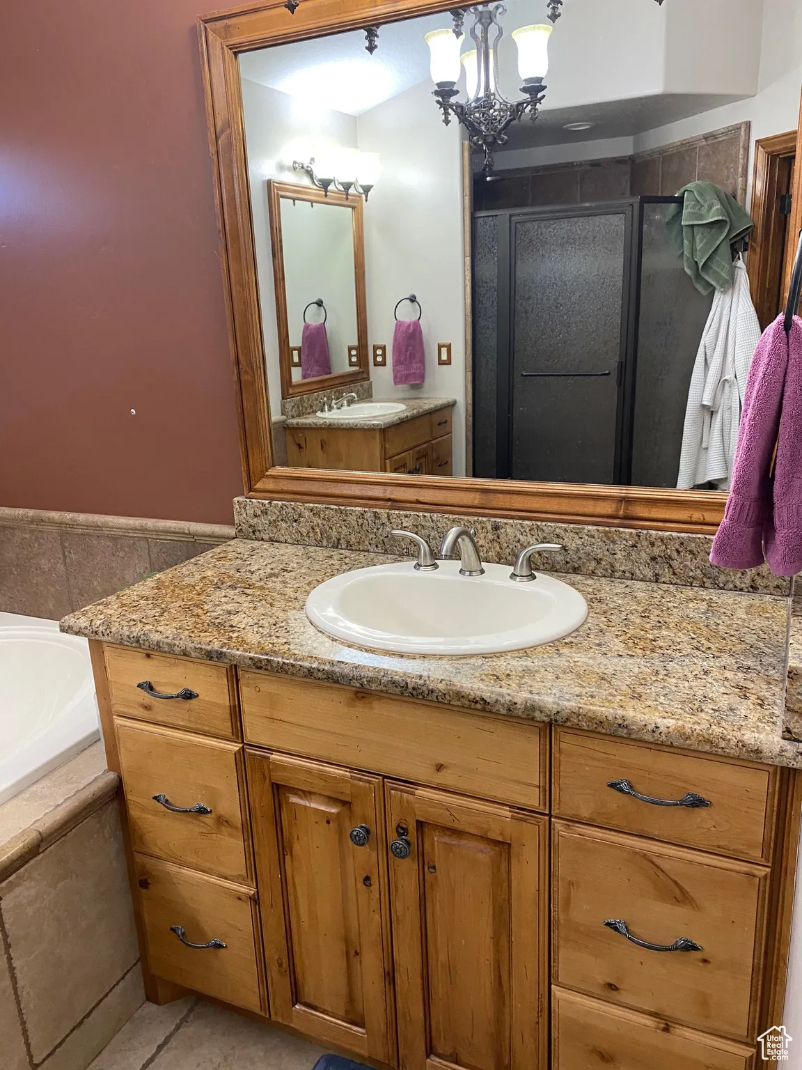 Bathroom featuring vanity, a bath, a shower stall, a chandelier, and tile patterned flooring
