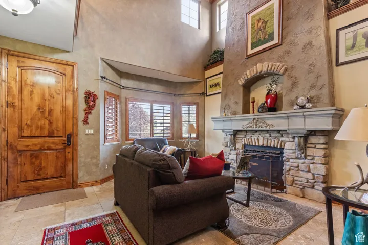 Living room with a towering ceiling, a fireplace, and tile patterned floors