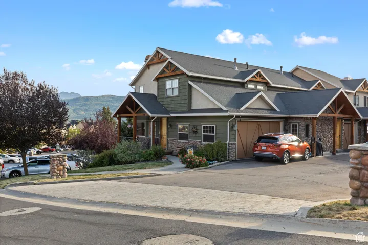 Craftsman-style home featuring stone siding, concrete driveway, and a mountain view