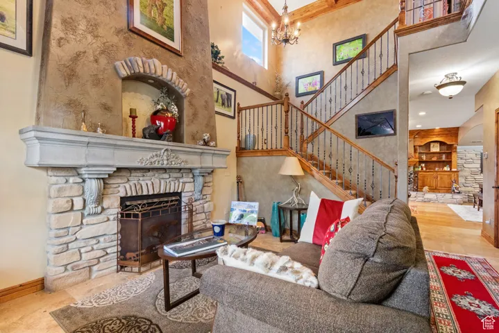 Living room featuring a fireplace, a towering ceiling, a chandelier, and stairs