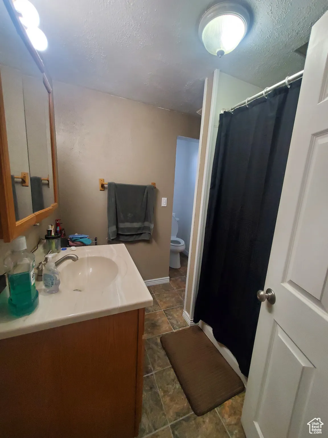 Full bath featuring vanity, a textured ceiling, and a stall shower