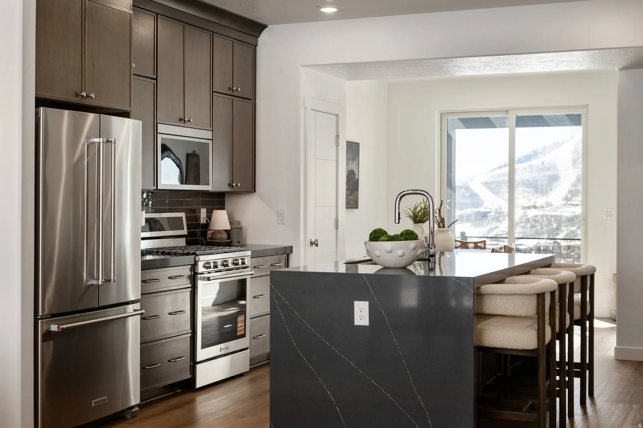 Kitchen featuring stainless steel appliances, a center island with sink, dark wood finished floors, and a breakfast bar area