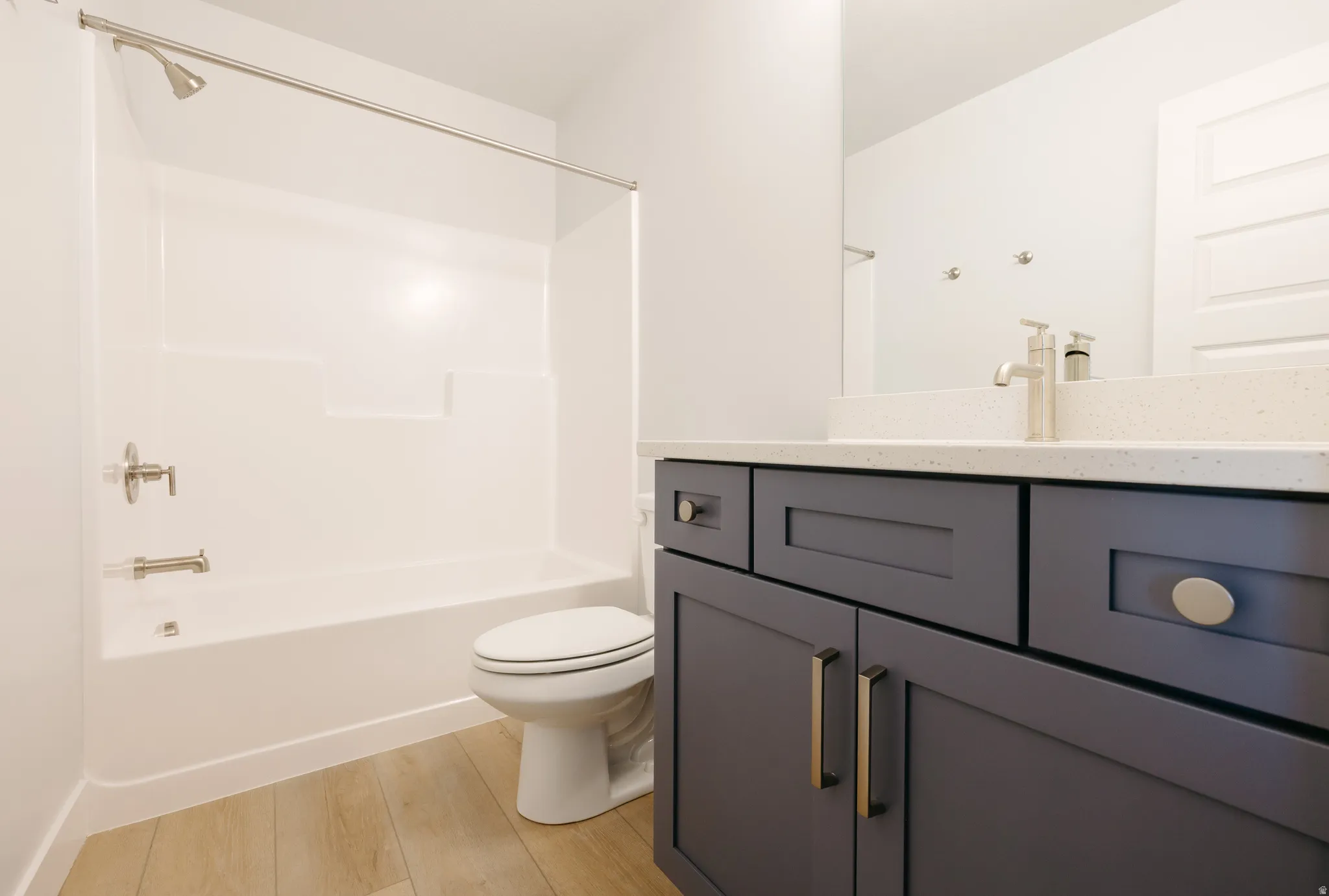 Bathroom featuring vanity, shower / bath combination, and light wood-type flooring