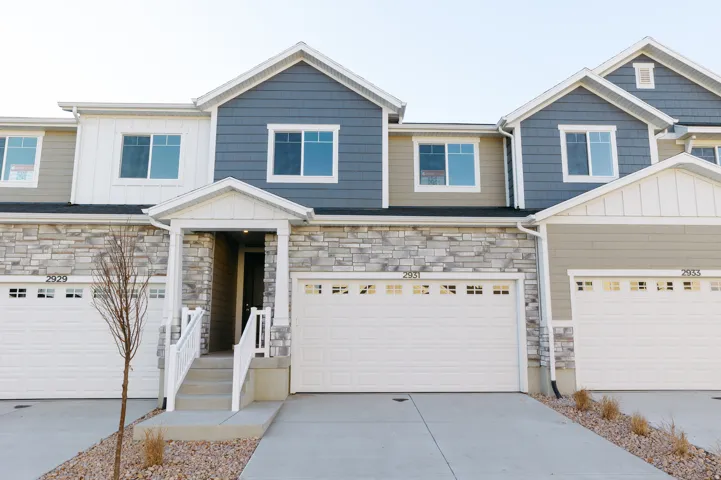 Craftsman-style home with stone siding, board and batten siding, driveway, and a garage