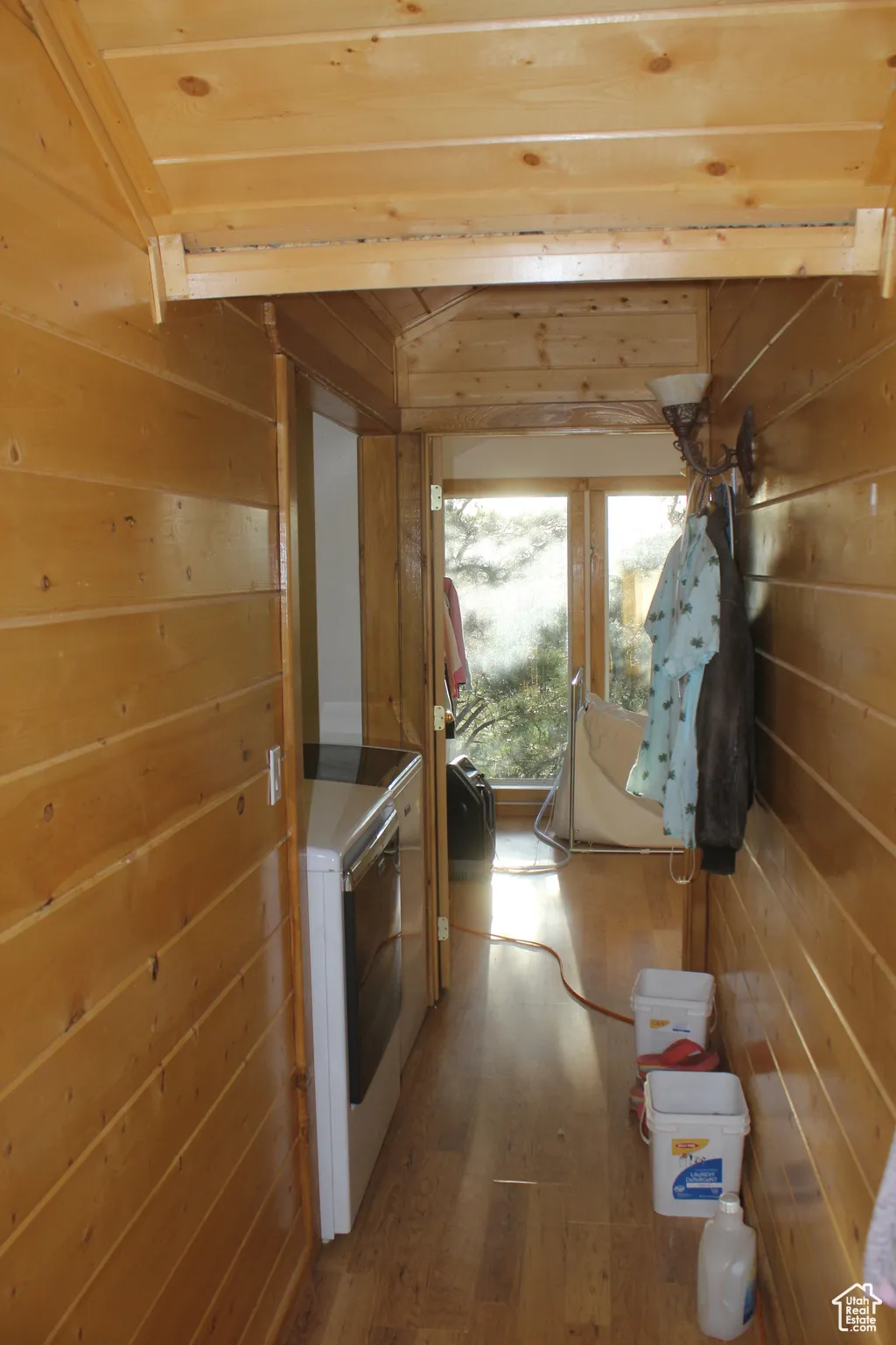 Corridor with wood walls, wood finished floors, washing machine and dryer, and wooden ceiling
