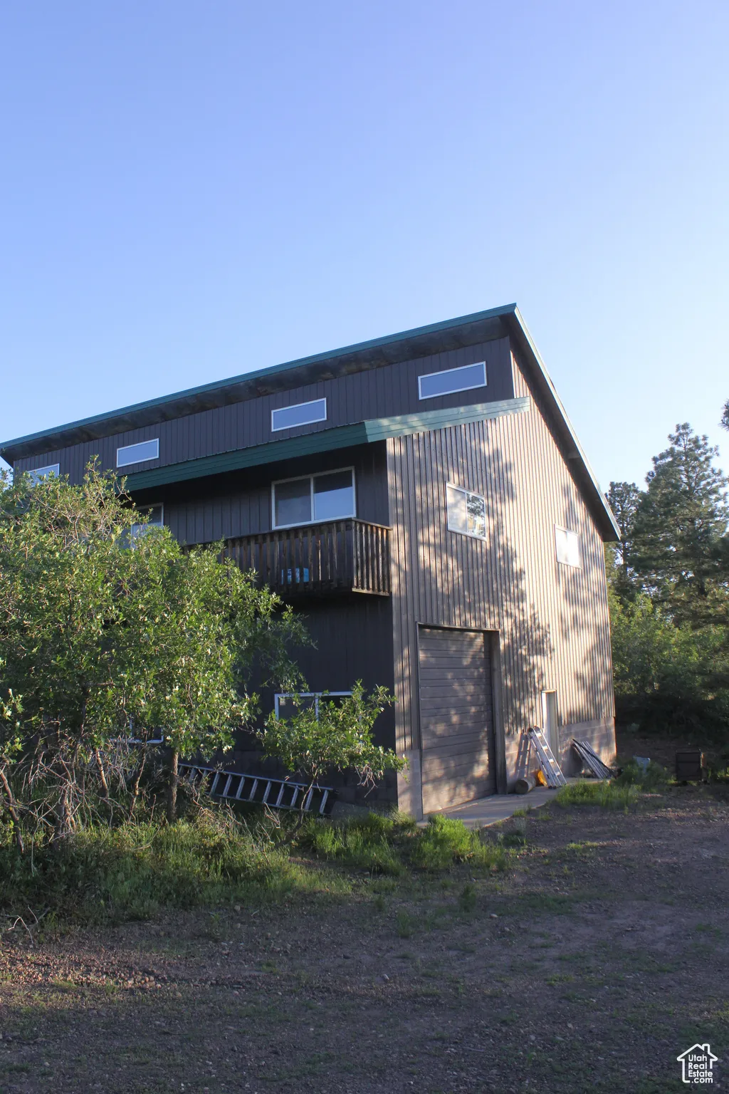 Rear view of property featuring a balcony, a garage, and driveway