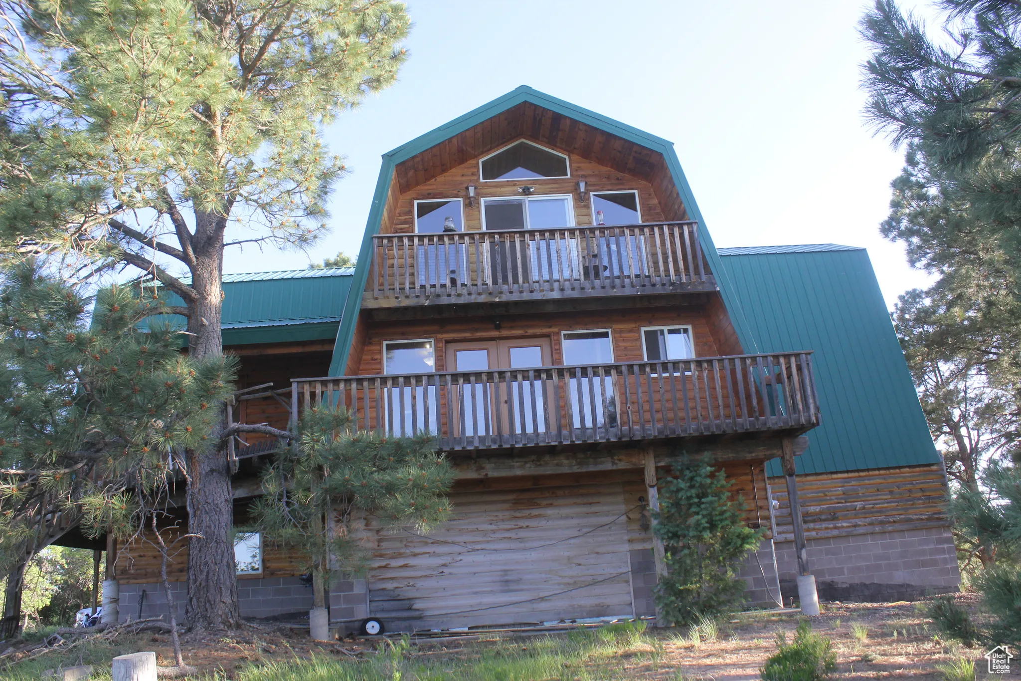 Rear view of house featuring a gambrel roof, a balcony, and a metal roof