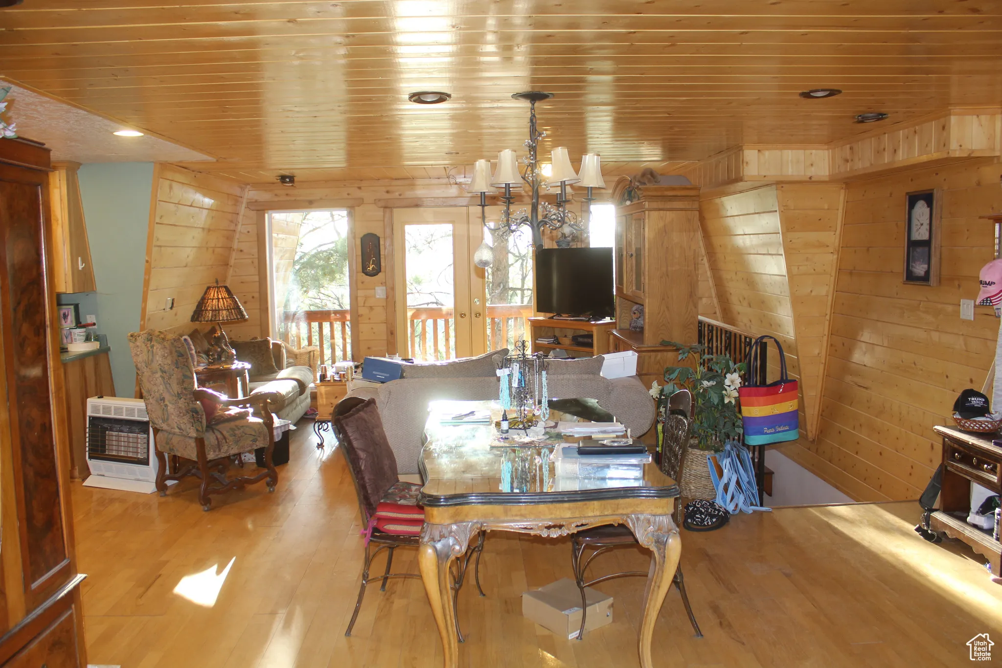 Dining room featuring wood walls, wooden ceiling, heating unit, wood finished floors, and a chandelier