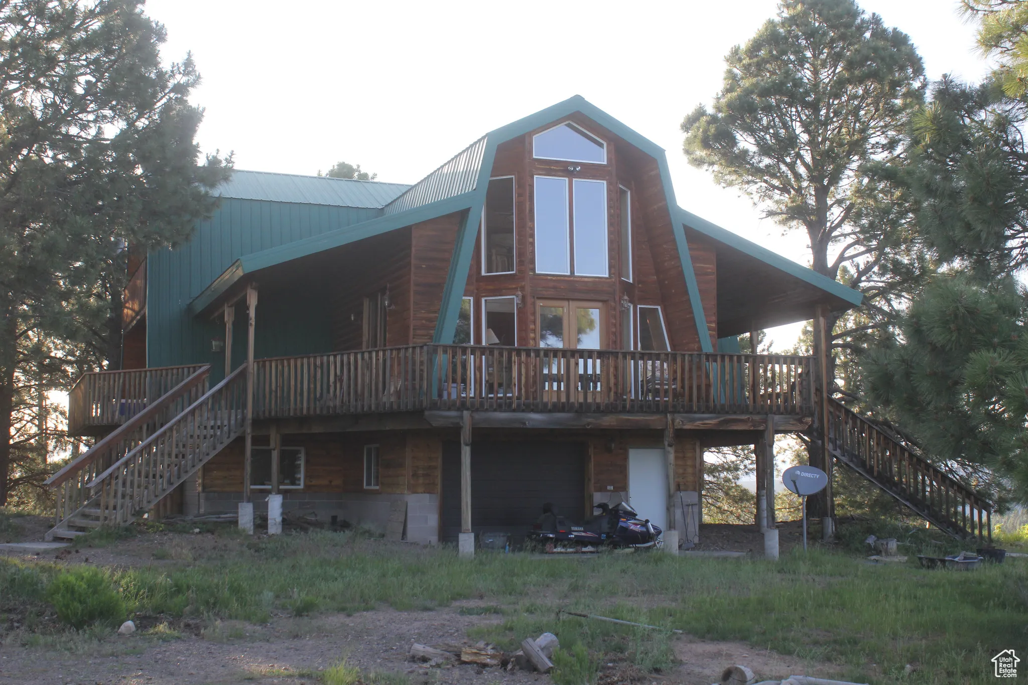 Back of property with stairway, a deck, a gambrel roof, and a metal roof