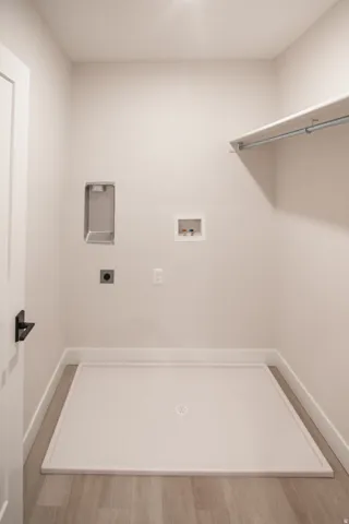 Laundry area with hookup for a washing machine, light wood-style floors, and electric dryer hookup