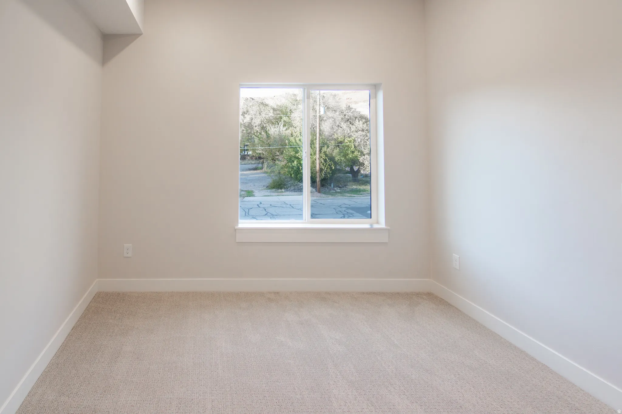Unfurnished room featuring light carpet and baseboards