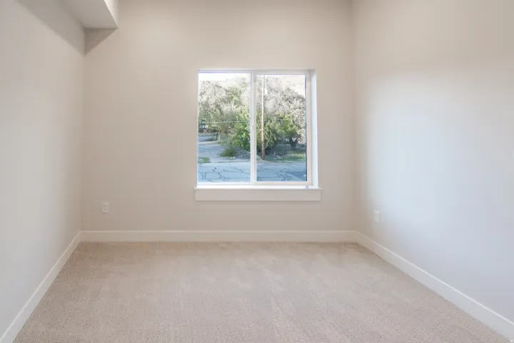 Unfurnished room featuring light carpet and baseboards