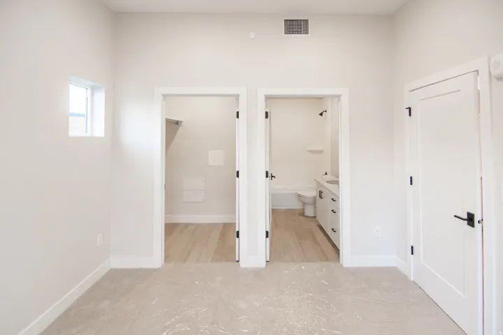 Unfurnished bedroom featuring connected bathroom, light carpet, and a walk in closet