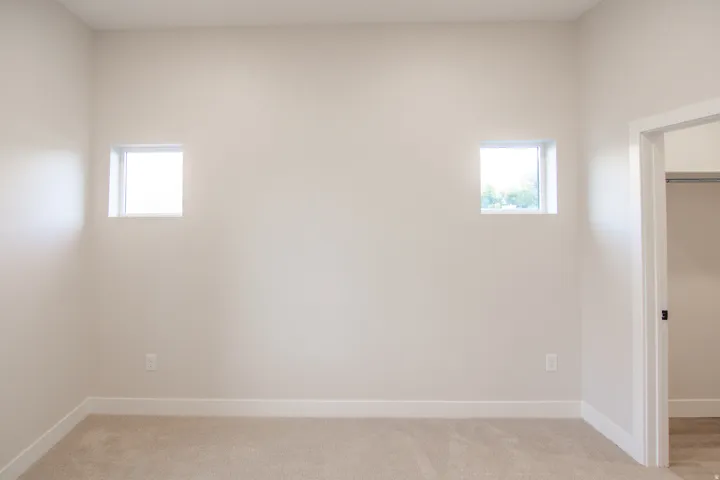 Empty room with light colored carpet and baseboards