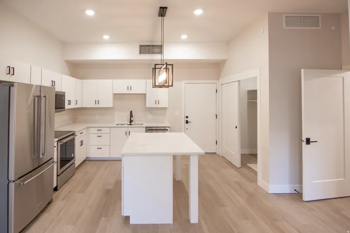 Kitchen featuring stainless steel appliances, white cabinetry, light wood-style floors, decorative light fixtures, and recessed lighting