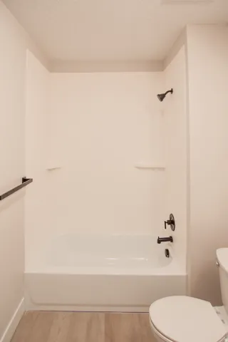 Full bathroom with a textured ceiling, bathtub / shower combination, and light wood-type flooring