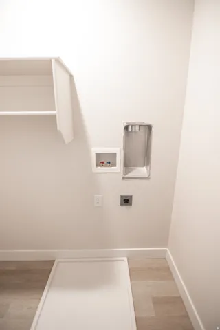 Laundry area with hookup for a washing machine, electric dryer hookup, and light wood-style flooring