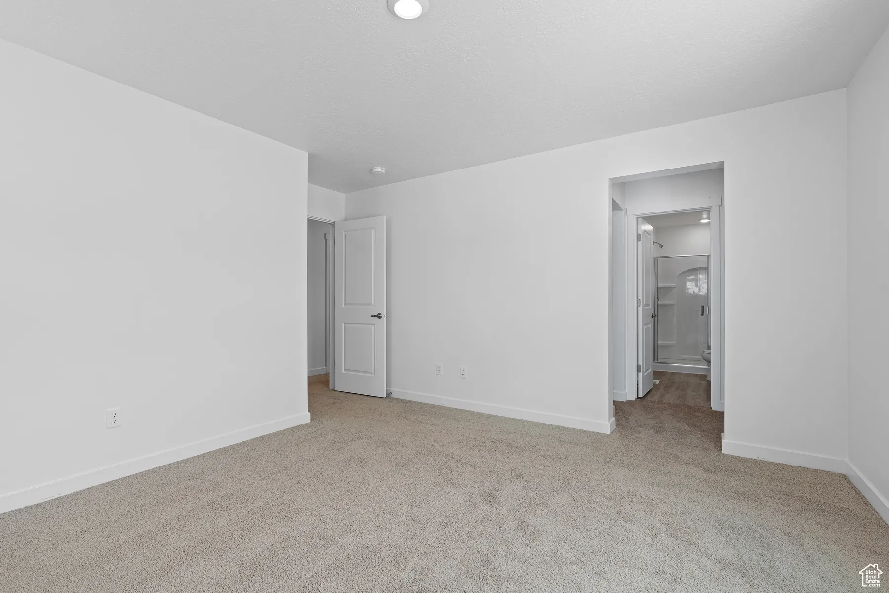 Unfurnished bedroom with light colored carpet and connected bathroom