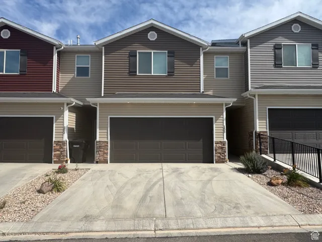View of front of home featuring concrete driveway, stone siding, and an attached garage