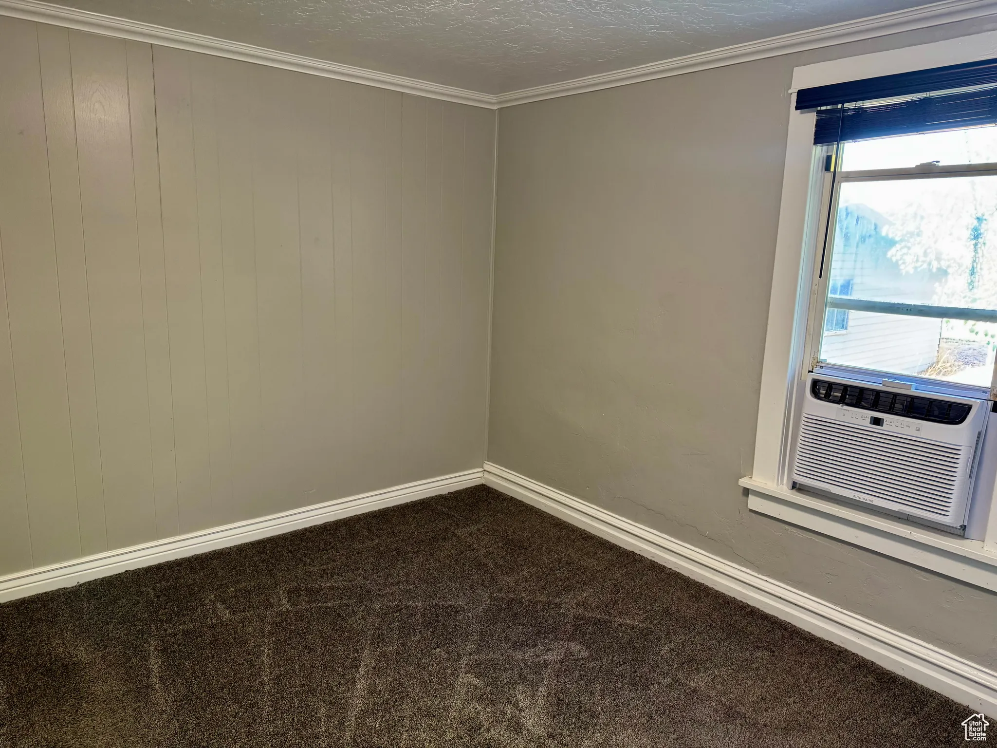 Spare room featuring a textured ceiling, ornamental molding, and dark carpet