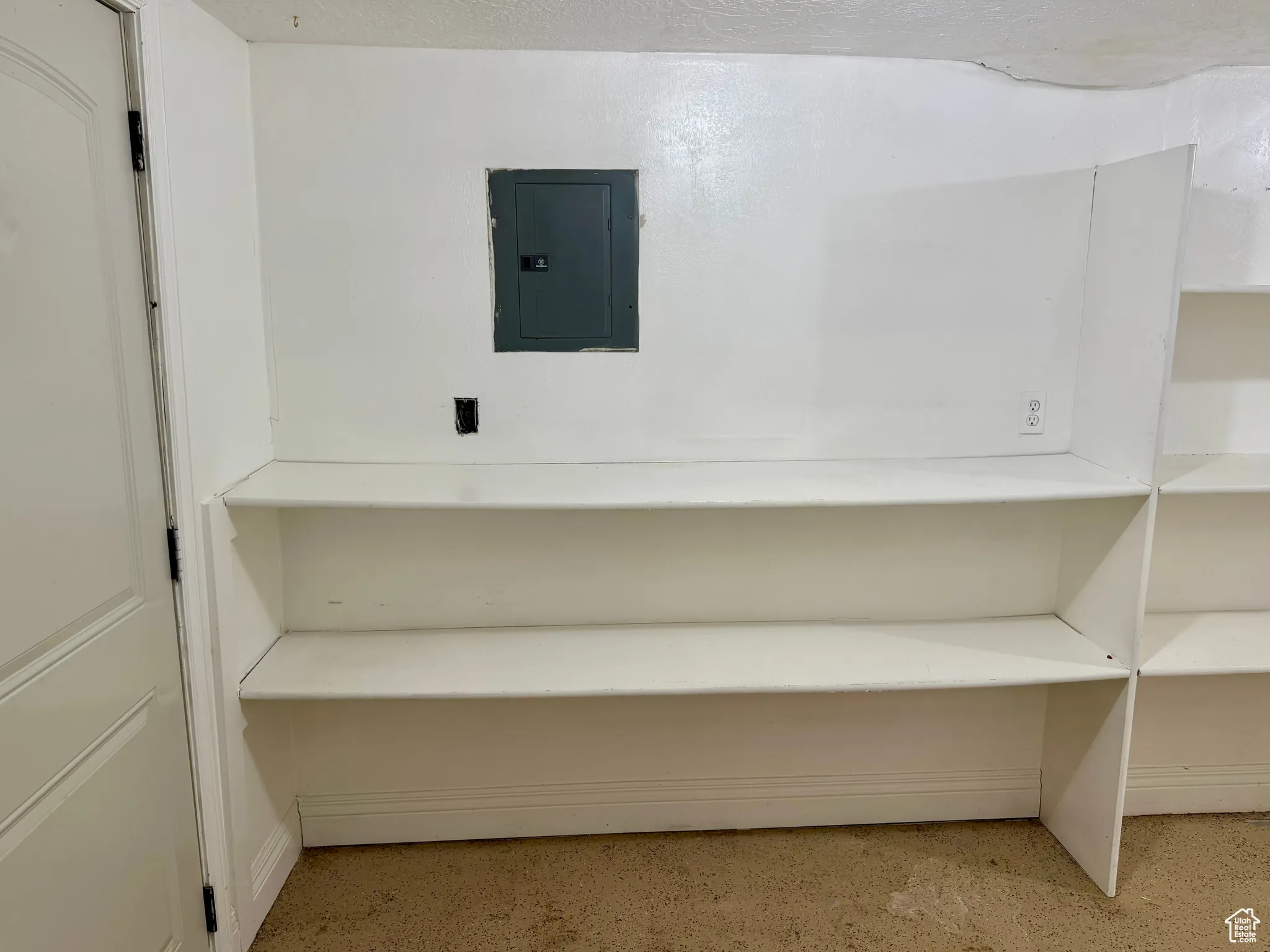 Misc room with electric panel, dark speckled floor, and a textured ceiling