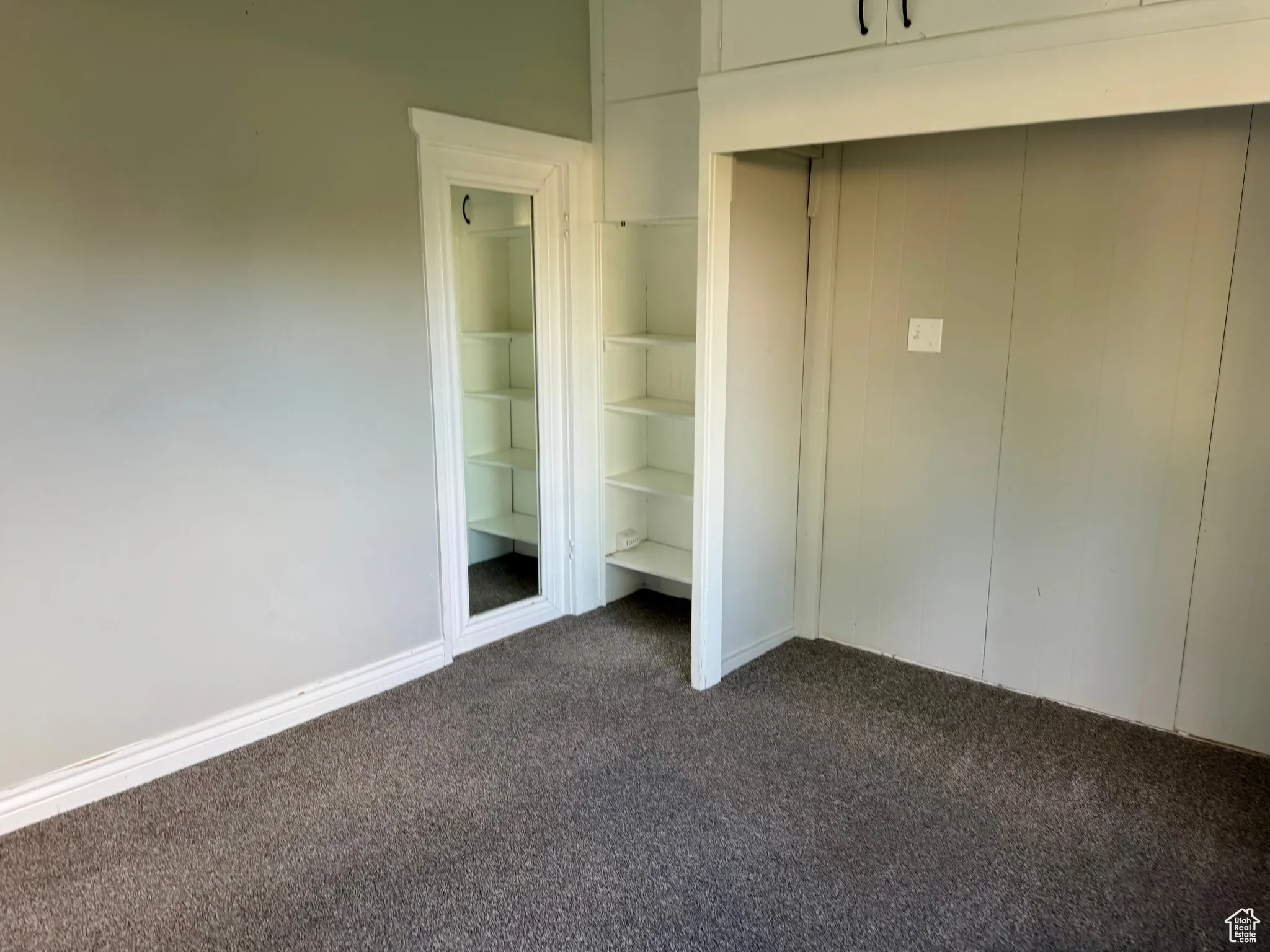 Unfurnished bedroom featuring dark carpet and baseboards