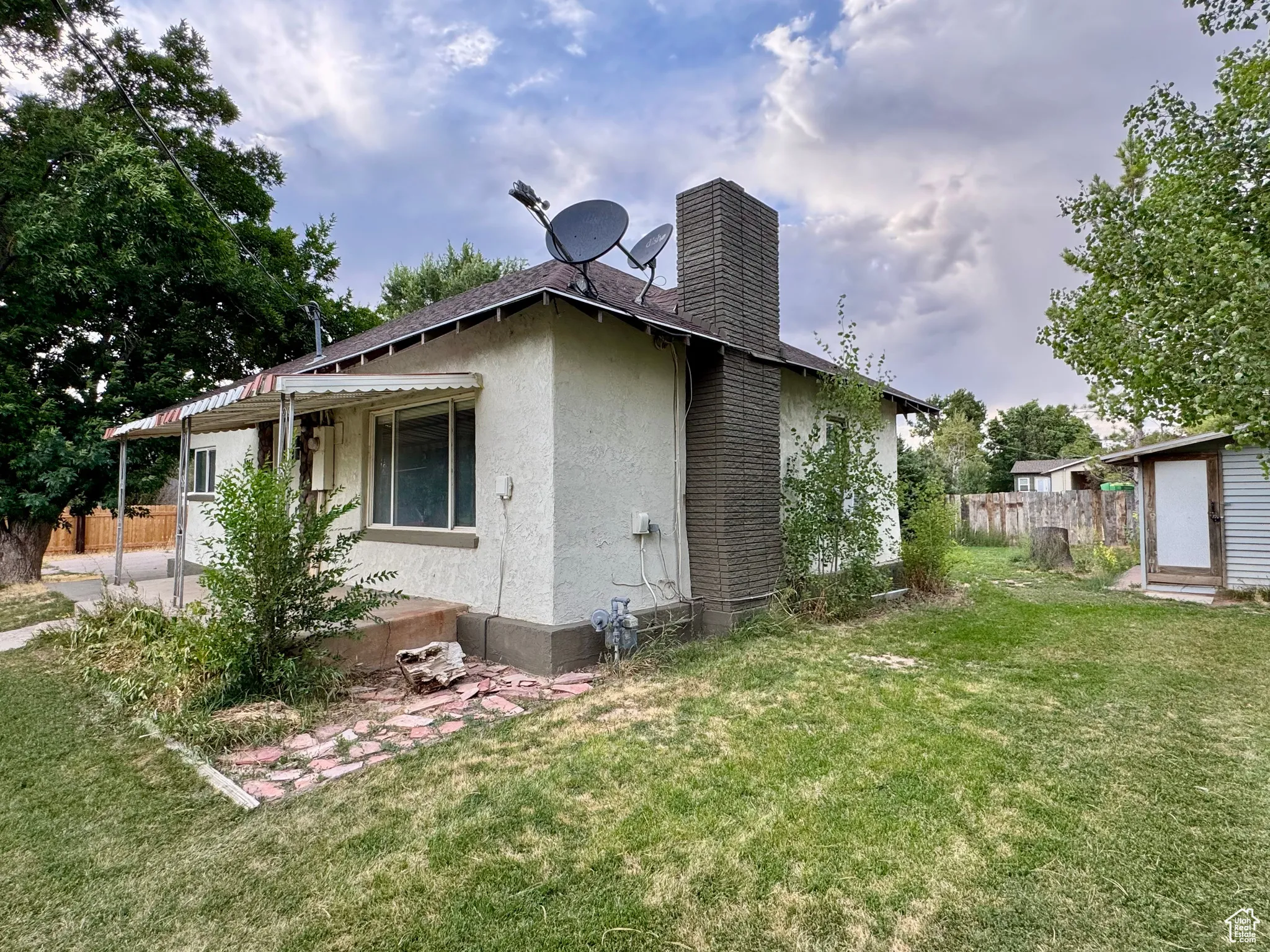 Rear view of house with stucco siding and a chimney