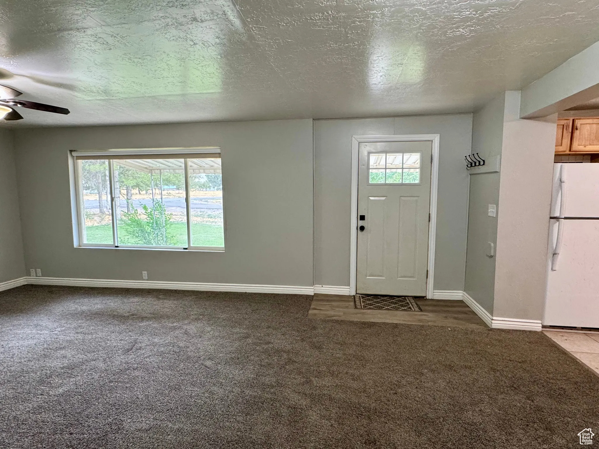Foyer with a textured ceiling, dark carpet, and ceiling fan