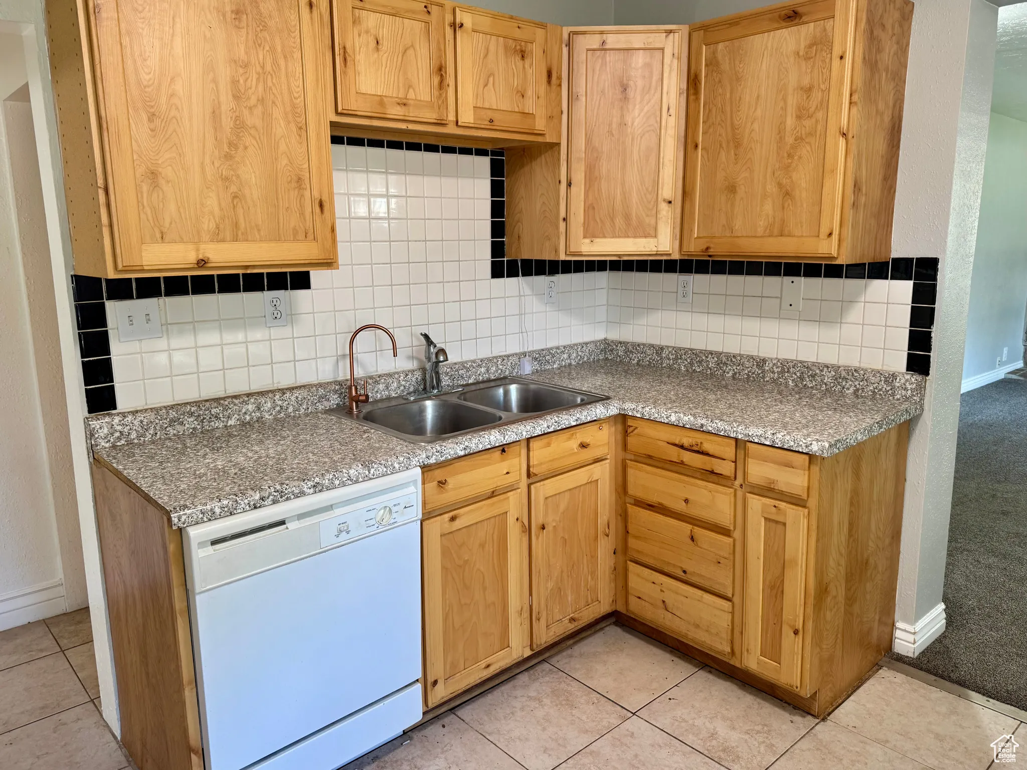 Kitchen featuring tasteful backsplash, dishwasher, light tile patterned floors, and light countertops