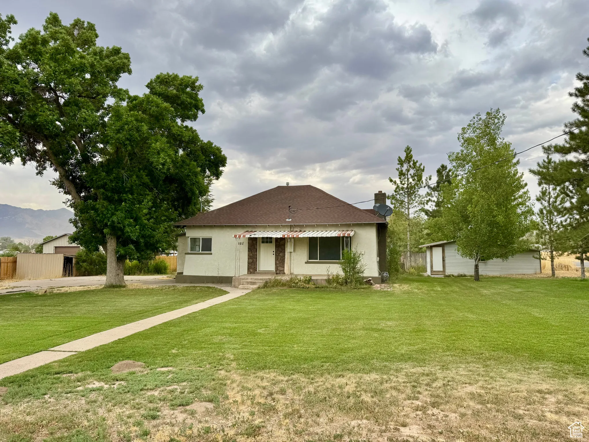 View of front of home featuring a front yard, a chimney, and an outdoor structure