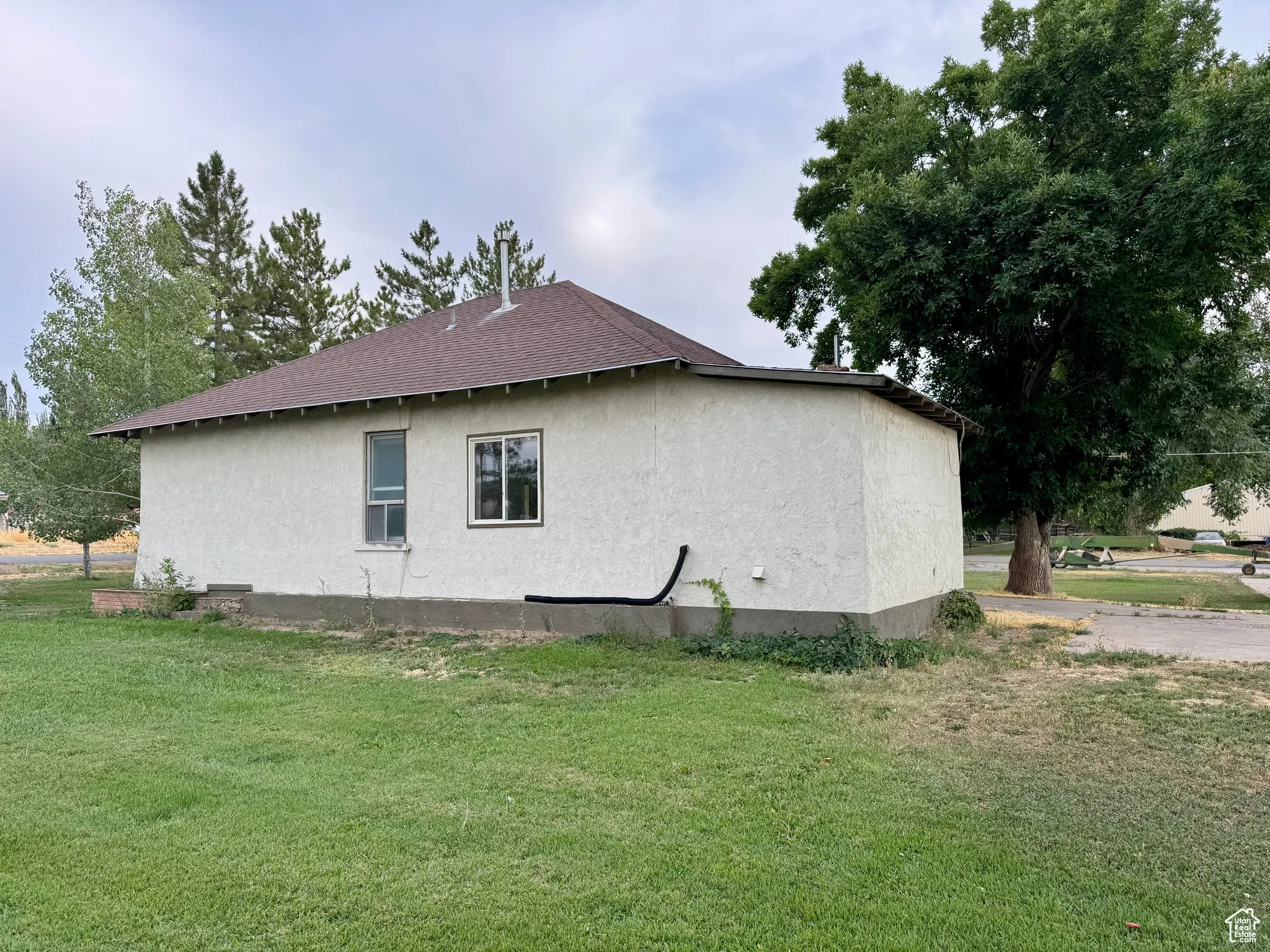 View of home's exterior featuring a yard, stucco siding, and roof with shingles