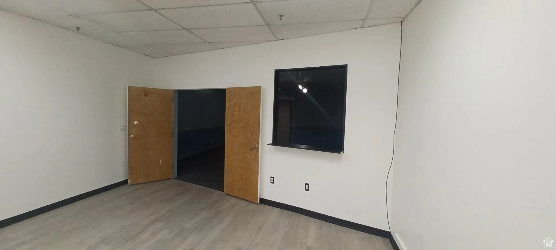 Unfurnished room featuring wood finished floors and a drop ceiling