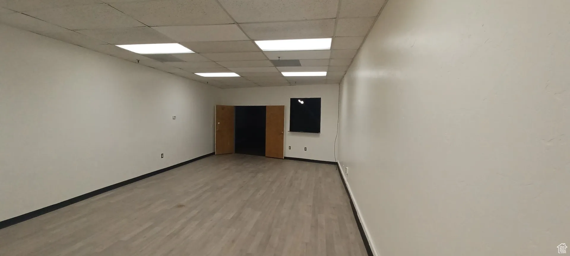 Empty room with light wood finished floors and a drop ceiling