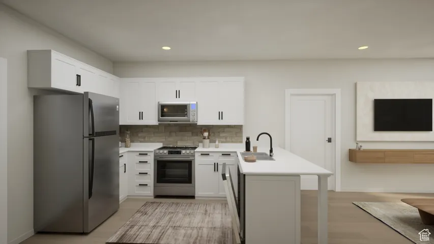 Kitchen with appliances with stainless steel finishes, a peninsula, light countertops, recessed lighting, and light wood-style flooring