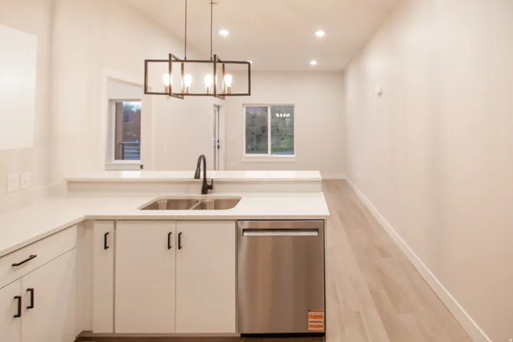 Kitchen featuring dishwasher, recessed lighting, decorative light fixtures, light wood-type flooring, and a peninsula