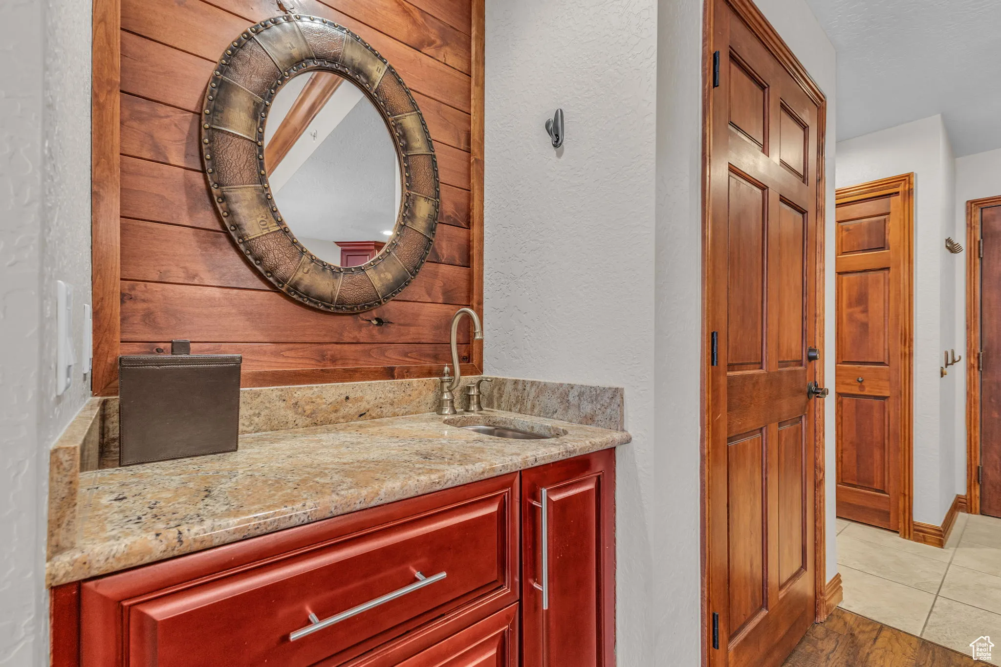 Bathroom with vanity, a textured wall, wood walls, and light tile patterned floors
