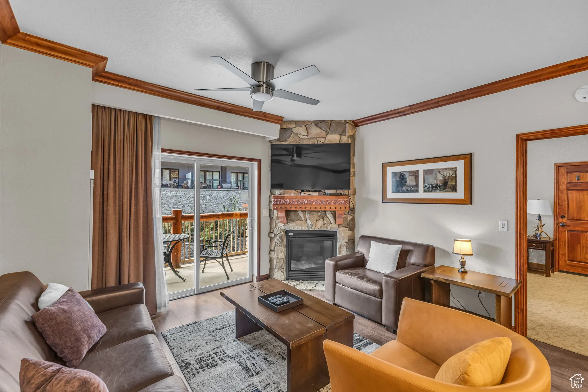 Living area featuring crown molding, a fireplace, wood finished floors, ceiling fan, and a textured ceiling