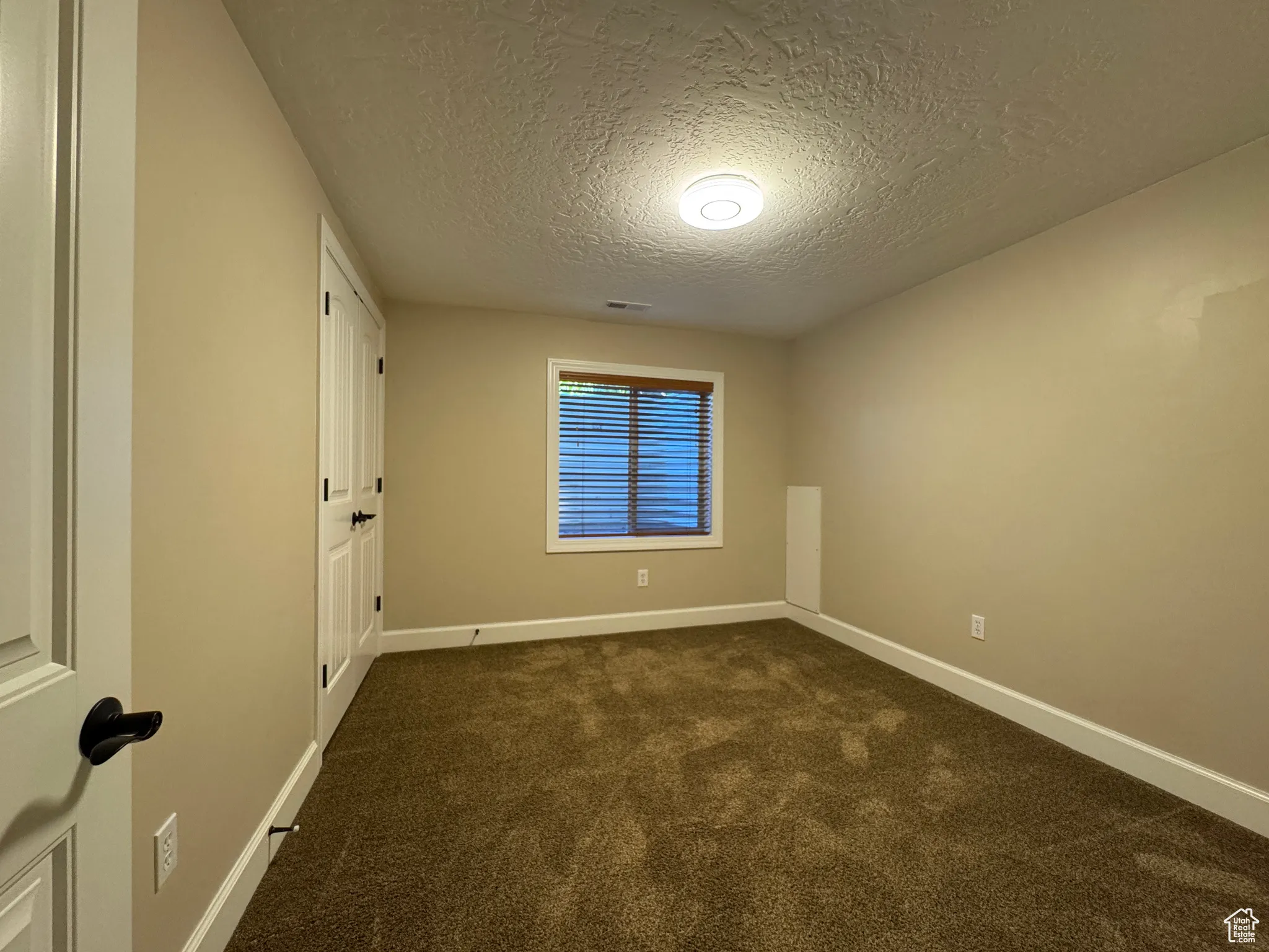 Unfurnished room with dark carpet and a textured ceiling