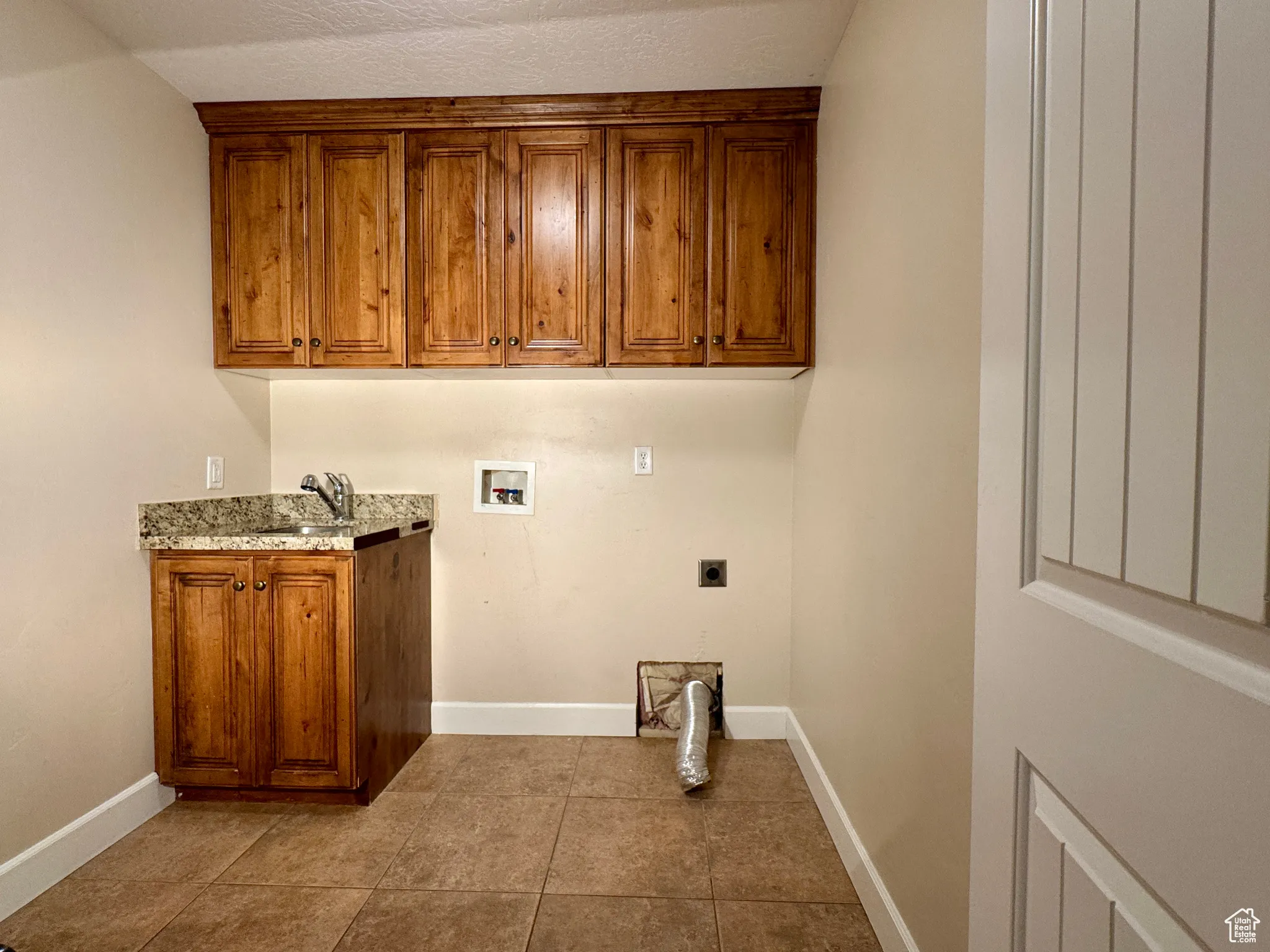 Laundry area featuring hookup for a washing machine, dark tile patterned floors, cabinet space, and electric dryer hookup