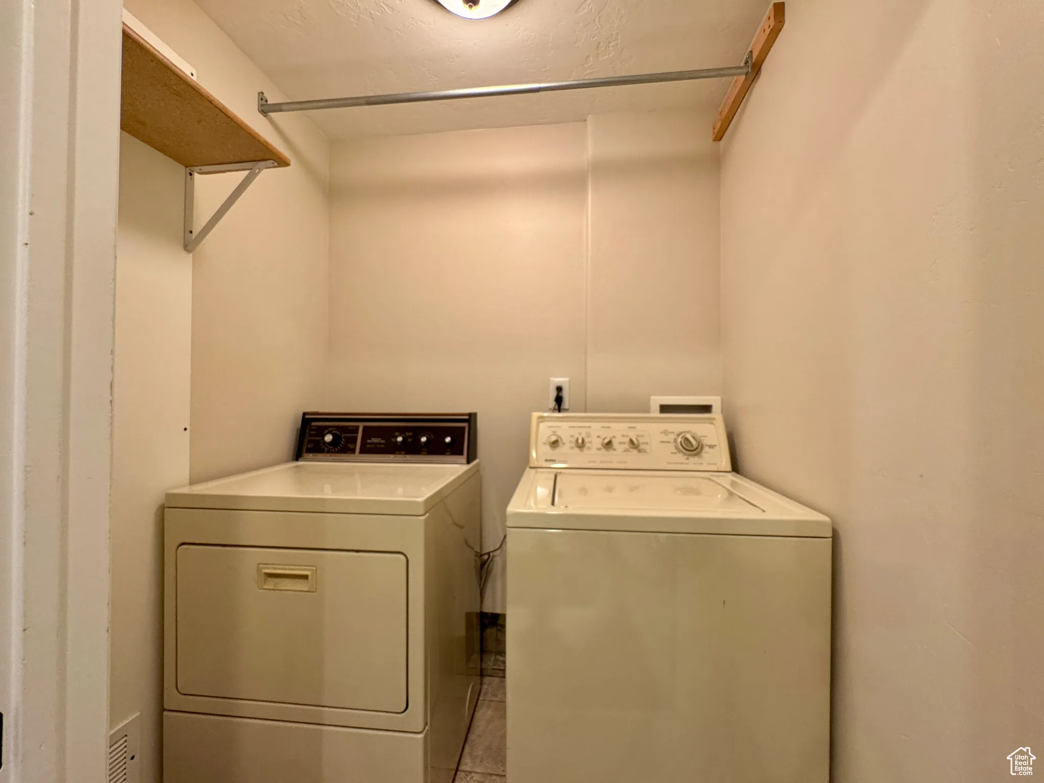Laundry room featuring tile patterned floors, washer and clothes dryer, and a textured ceiling